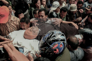 Ratusan pelayat sudah menunggu di rumah duka. Histeris tak terbendung dan tak terhitung lagi sumpah serapah yang keluar dari mulut kerabat korban yang begitu pilu menyaksikan kejadian tragis tersebut. Semua ingin menggapai, semua merasa berhak menyentuh korban sebagai bentuk solidaritas. (Foto: bmzIMAGES/Basri Marzuki)