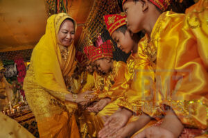Pemberian daun pacar dimulai. Seorang ibu menandai anaknya dengan mencipratkan daun pacar ke tangannya. (Foto: bmzIMAGEs/Basri Marzuki)