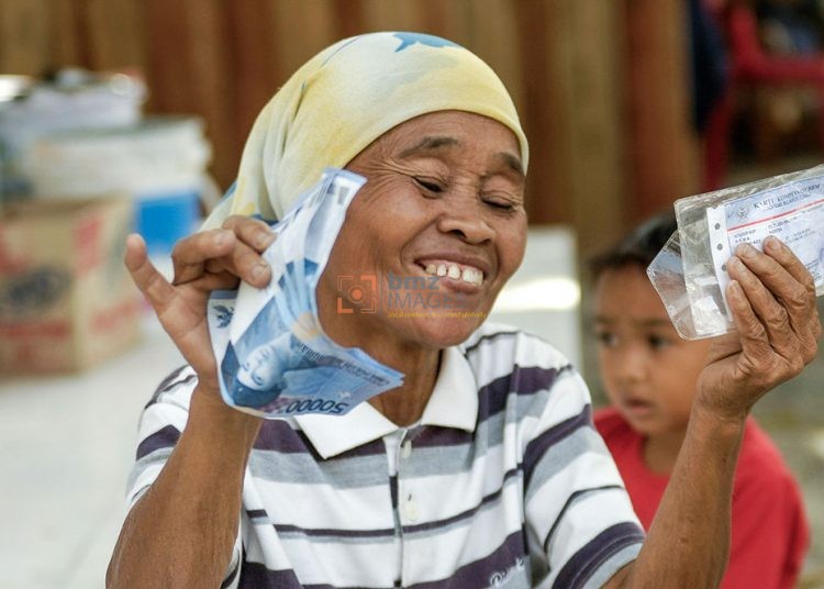 Seorang warga menunjukkan sejumlah lembaran uang yang baru saja diterimanya dari Kantor Pos Induk di Palu, Sulawesi Tengah, Kamis (14/12/2006). Uang tersebut adalah penyaluran keempat program Bantuan Langsung Tunai (BLT) tahun 2006 sebesar Rp300 ribu bagi setiap warga miskin setiap tiga bulan. Kantor Pos se Sulawesi Tengah menyalurkan sekitar Rp64 miliar dana BLT kepada lebih dari 200 ribu warga miskin setiap periode penyaluran. (bmzIMAGES/Basri Marzuki)